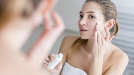 Woman applying cream on her face in a bathroom