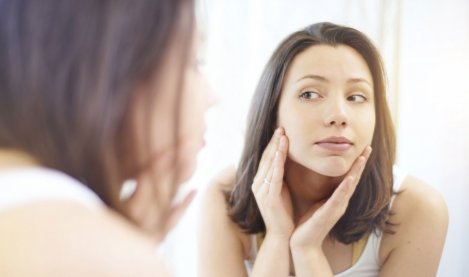 Woman checking her skin in a mirror