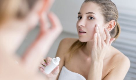 Woman applying cream on her face in a bathroom
